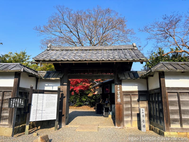 秋の青空の下、紅葉が覗く玄宮園の入口の様子