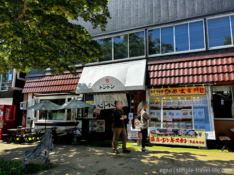 「ひめます料理」の黄色い看板と「トントン」ののれんが掛かる食堂の外観