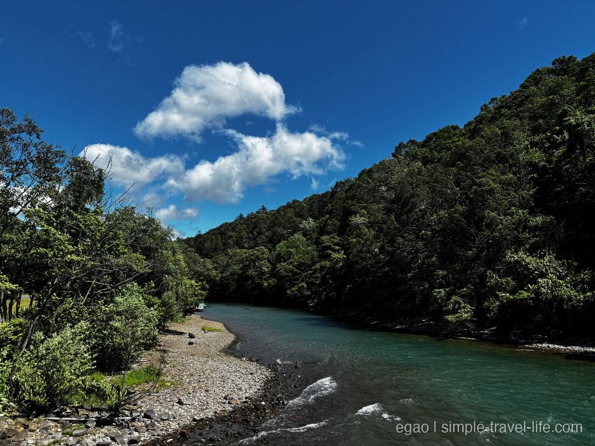 森に挟まれて流れる千歳川のエメラルドグリーンの水面と、石の河原