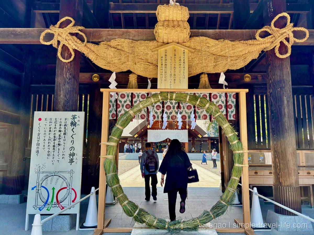 神門に設けられた青々とした茅の輪と、その先の拝殿へ向かう参拝者