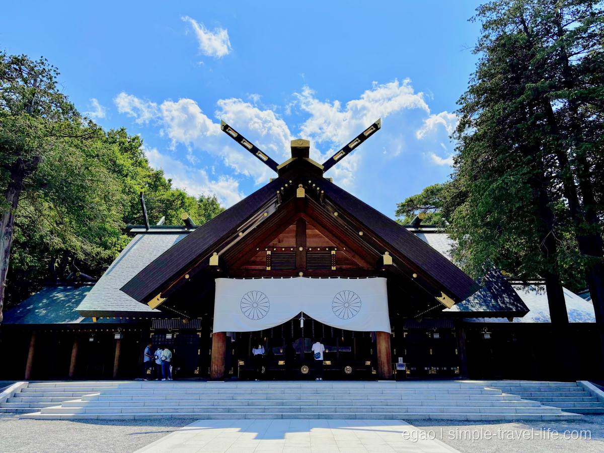 白い幕に菊の紋が入った北海道神宮の拝殿。大きな千木が空へ伸びる