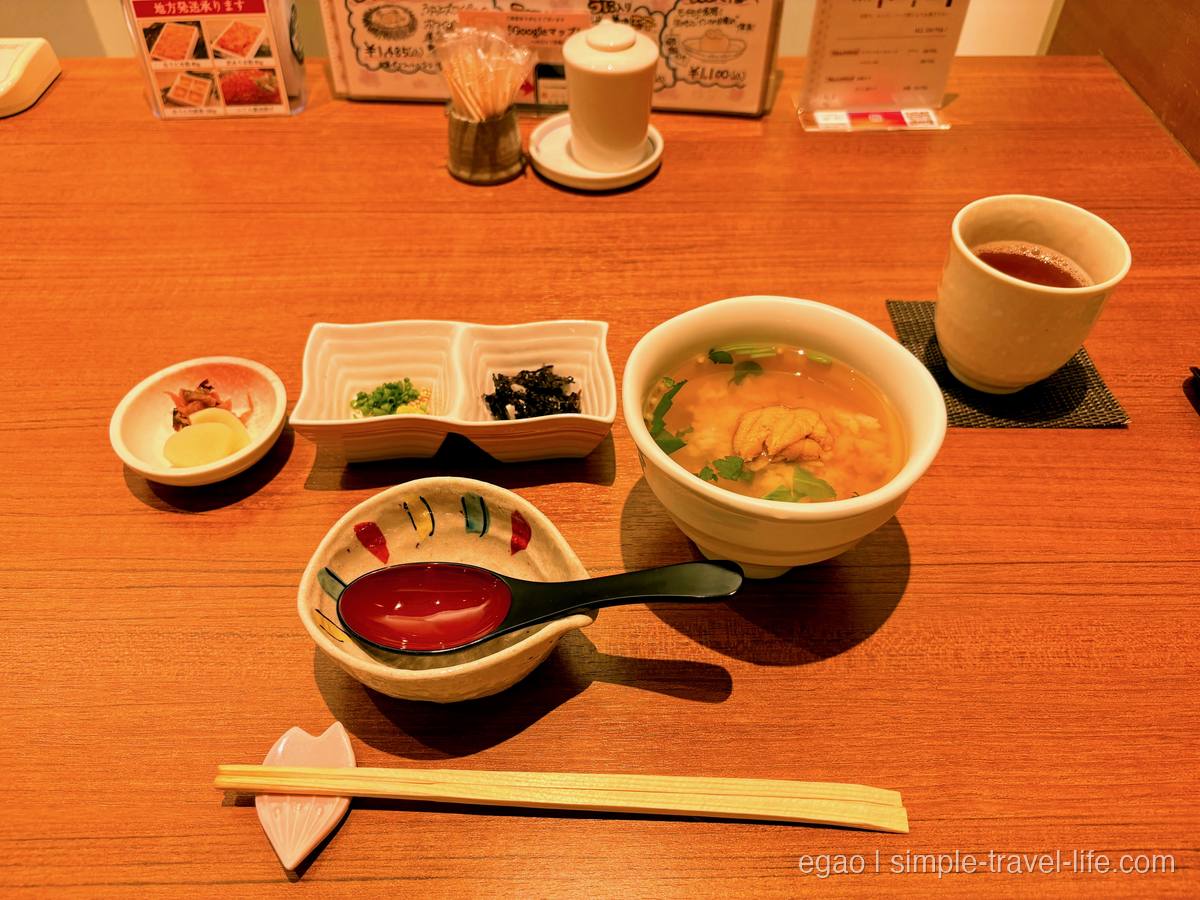 うにと三つ葉が浮かぶ椀に、刻みねぎと刻み海苔の薬味皿、小鉢が並んだ和食のお膳