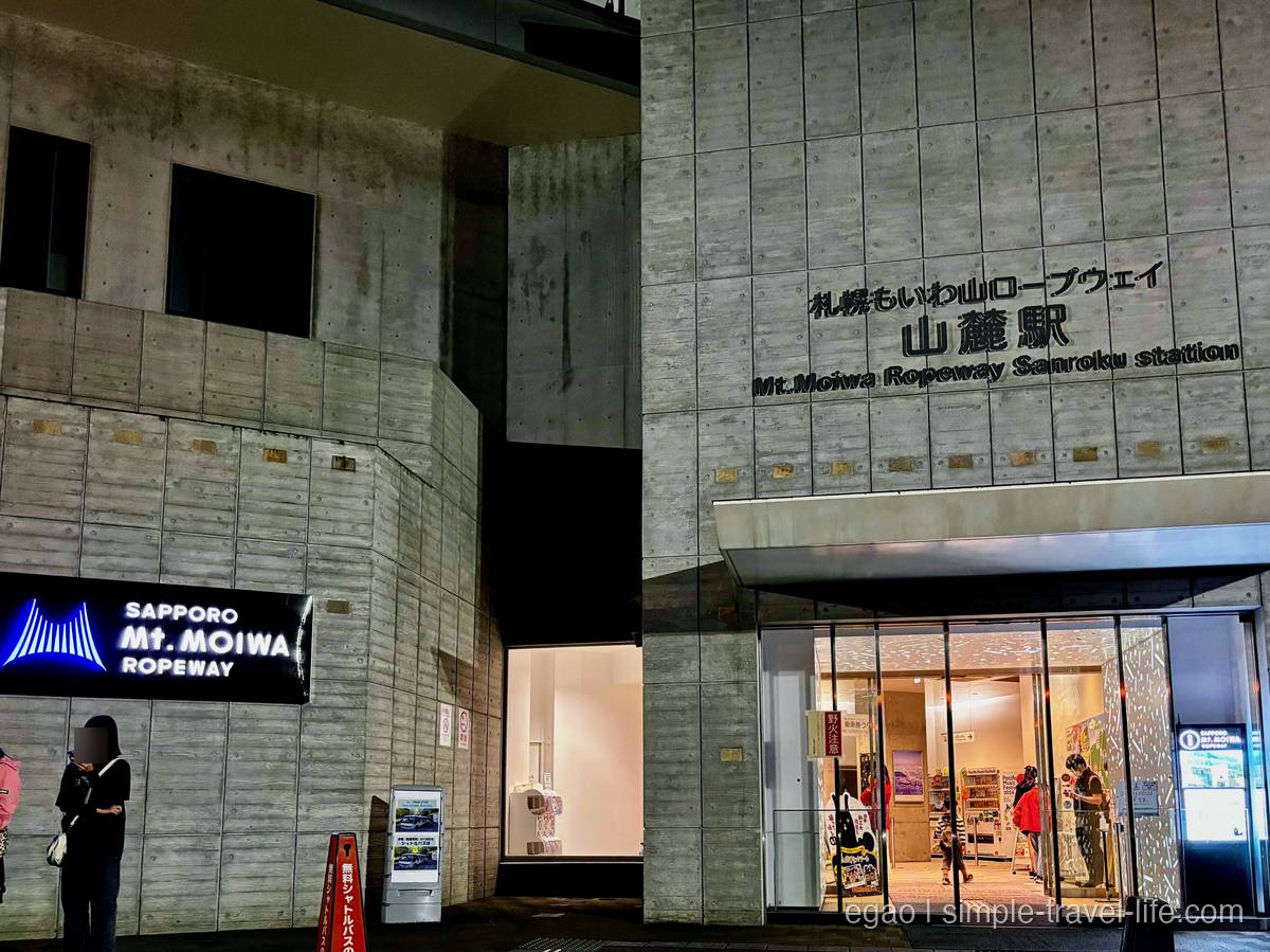 「札幌もいわ山ロープウェイ 山麓駅」と表示されたコンクリート造りの建物と、明かりのついた入口