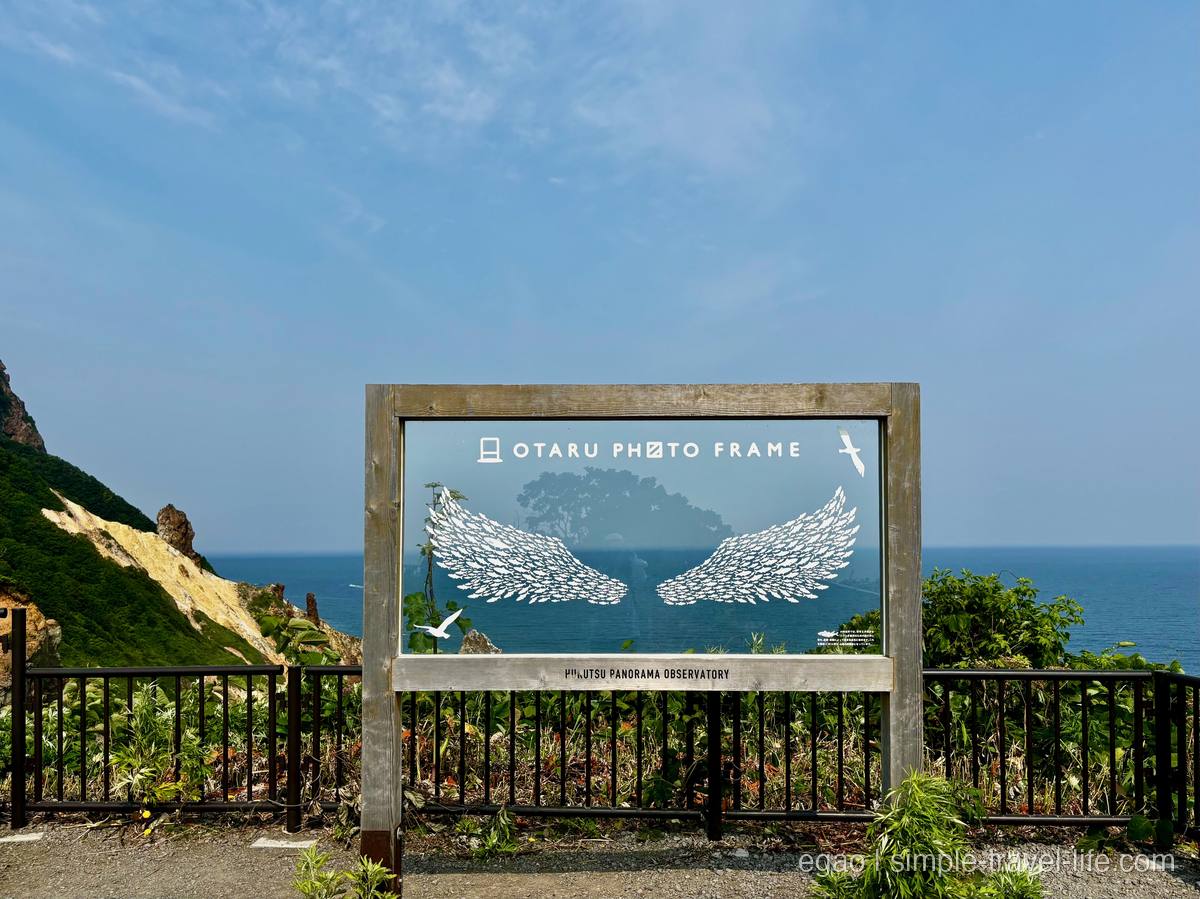 「OTARU PHOTO FRAME」と書かれた翼のイラスト入りの半透明パネルと、その向こうに広がる青い海