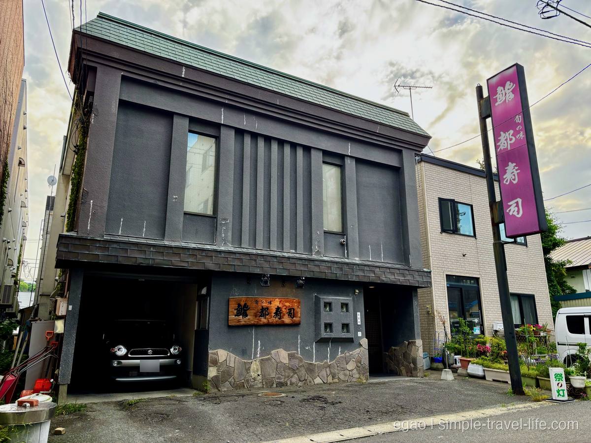小樽・花園の寿司店「都寿司」の黒い外壁と木の看板、ピンクの縦看板