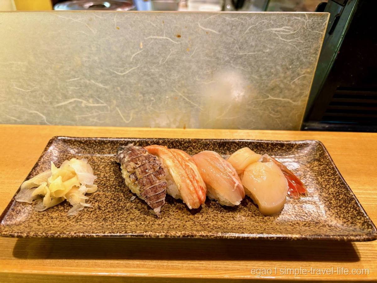 木のカウンターに置かれた角皿に並ぶ握り寿司4貫とガリ