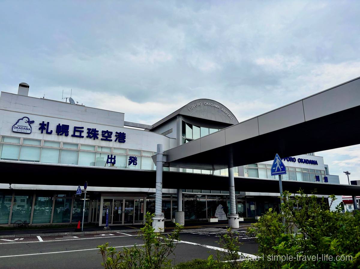 「札幌丘珠空港 出発」と掲げられた白い低層のターミナルビルと連絡通路