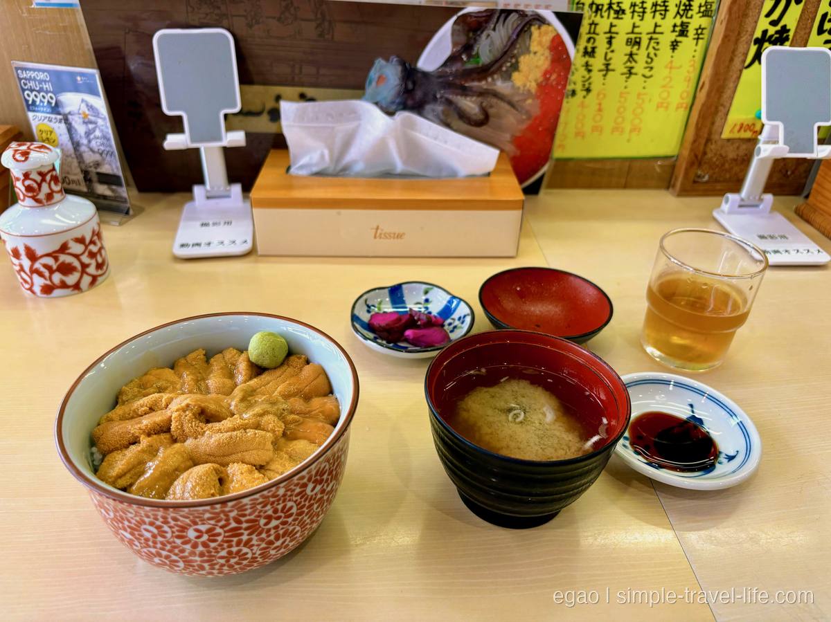 赤い花柄の丼いっぱいに敷き詰められたうにと、味噌汁・漬物・醤油の小皿