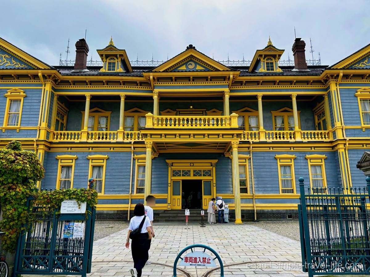 青灰色の壁に黄色い柱とベランダが映える、左右対称の木造洋館・旧函館区公会堂の正面