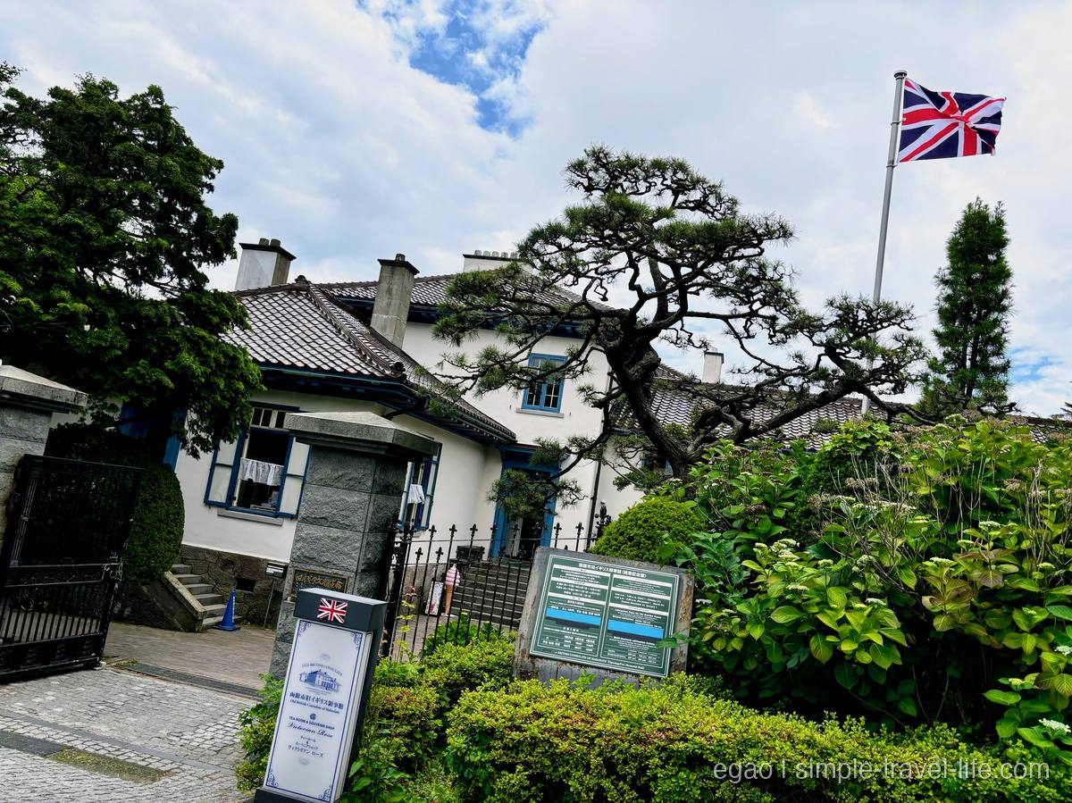函館市旧イギリス領事館。青い窓枠の白い洋館と和瓦の屋根、はためくユニオンジャック