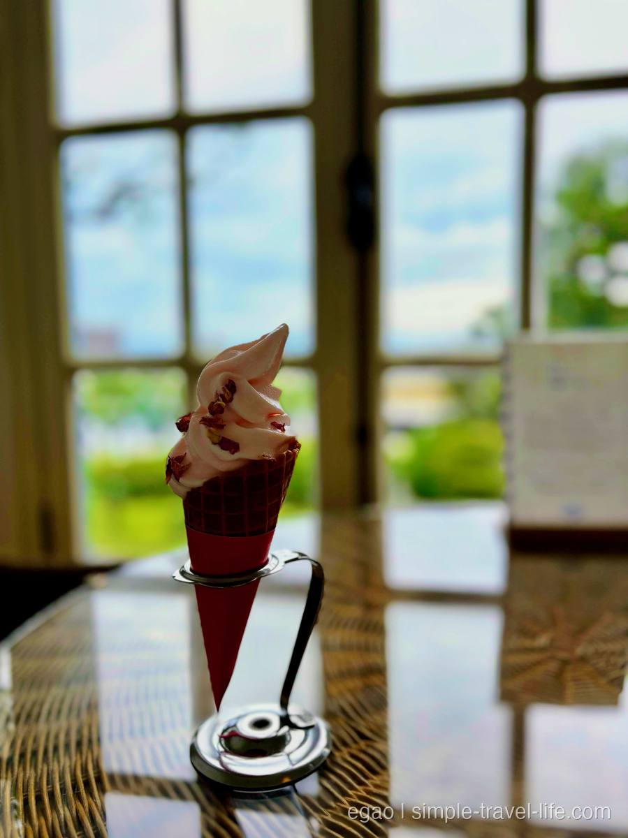 赤いコーンに盛られたピンクのソフトクリーム。いちごの果肉が散らしてある