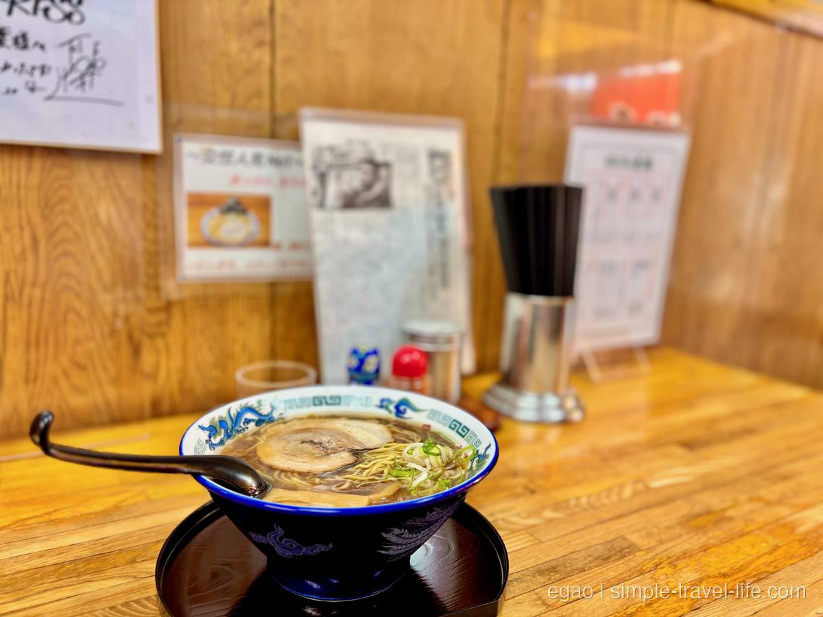 澄んだしょうゆ色のスープに縮れ麺、チャーシューとねぎ、メンマがのった一杯。青い龍模様の丼
