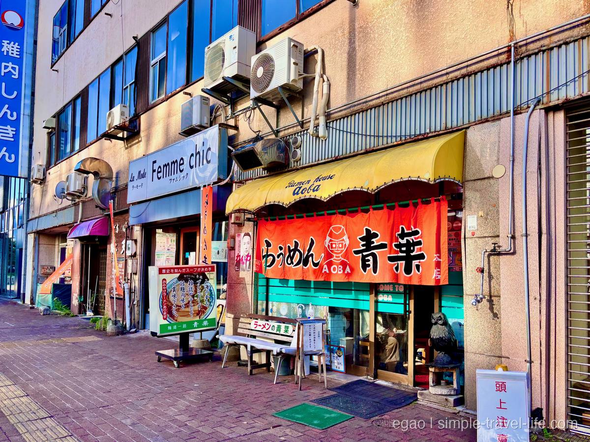 「らぅめん青葉」と染め抜かれた朱色の暖簾と黄色いテントが掛かる、ビル一階の店構え