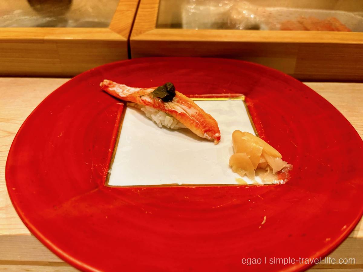 赤い皿にのった大ぶりのカニの握り一貫と、添えられたガリ
