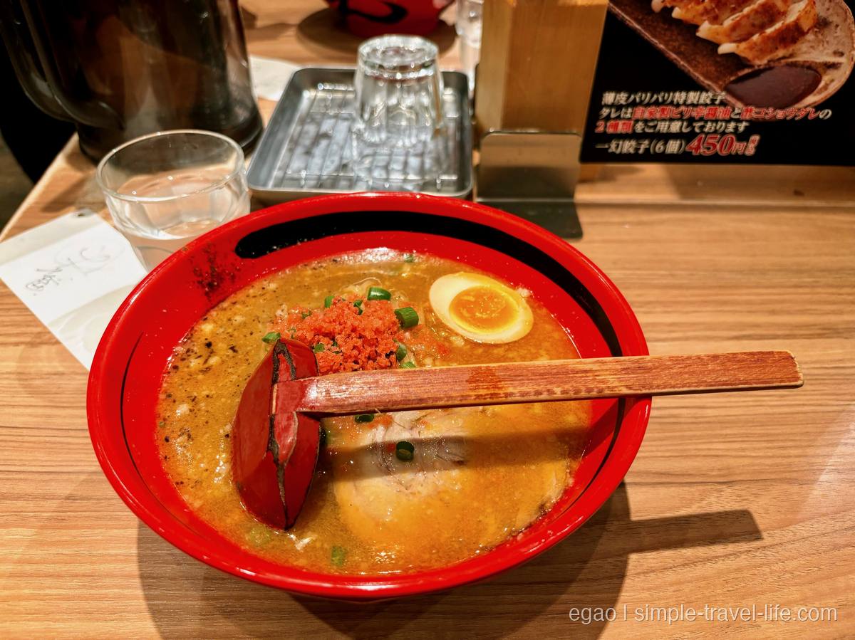 赤い丼に入ったえび味噌ラーメン。えびの粉と半熟の味玉、チャーシュー、青ねぎ